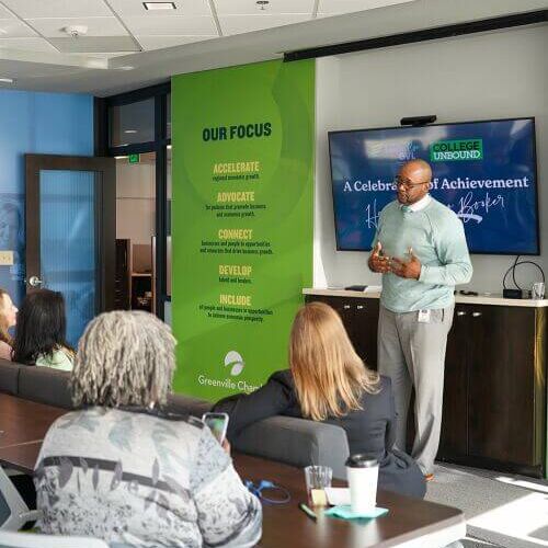 Speaker presenting to an audience next to a green TalentRise banner