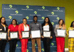Minority Business Accelerator graduates holding certificates in front of a Greenville Chamber backdrop