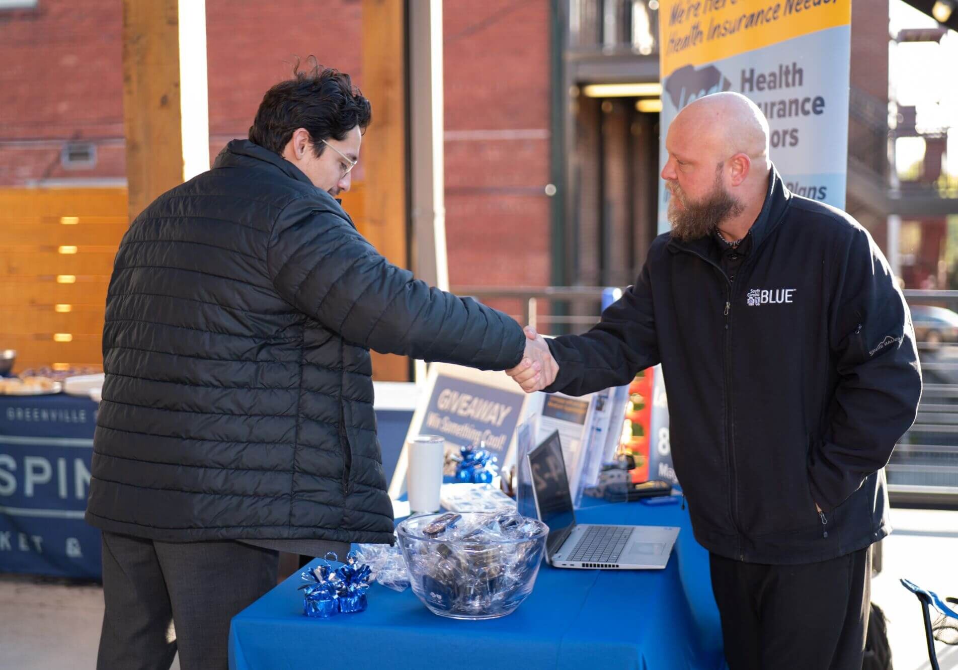 Attendees shaking hands at a sponsor table